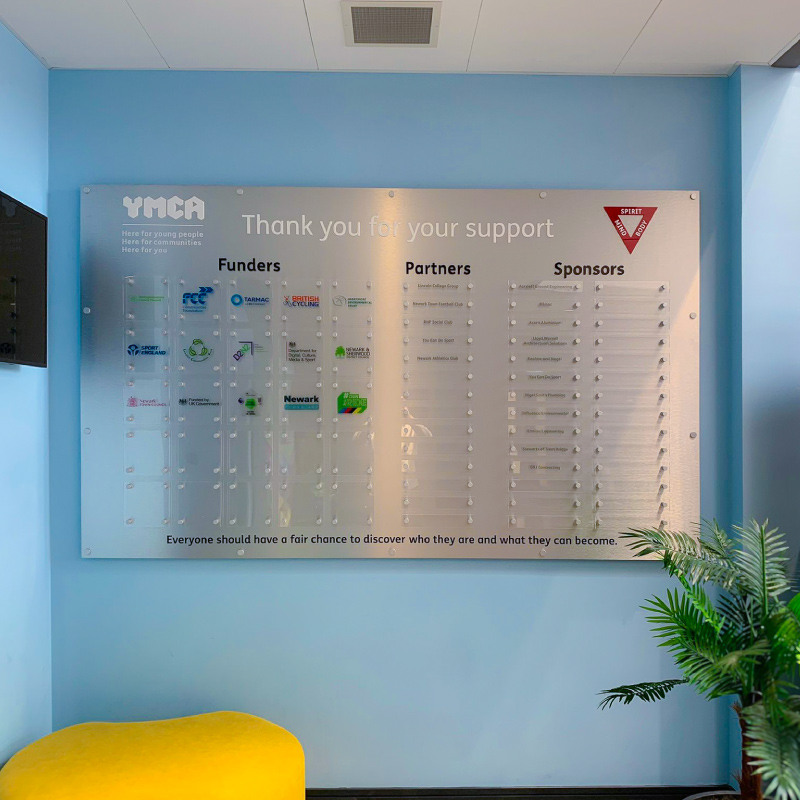An Acrylic display panel with smaller panels attached with standoffs. Each small panel has a logo for a YMCA funder or sponsor.